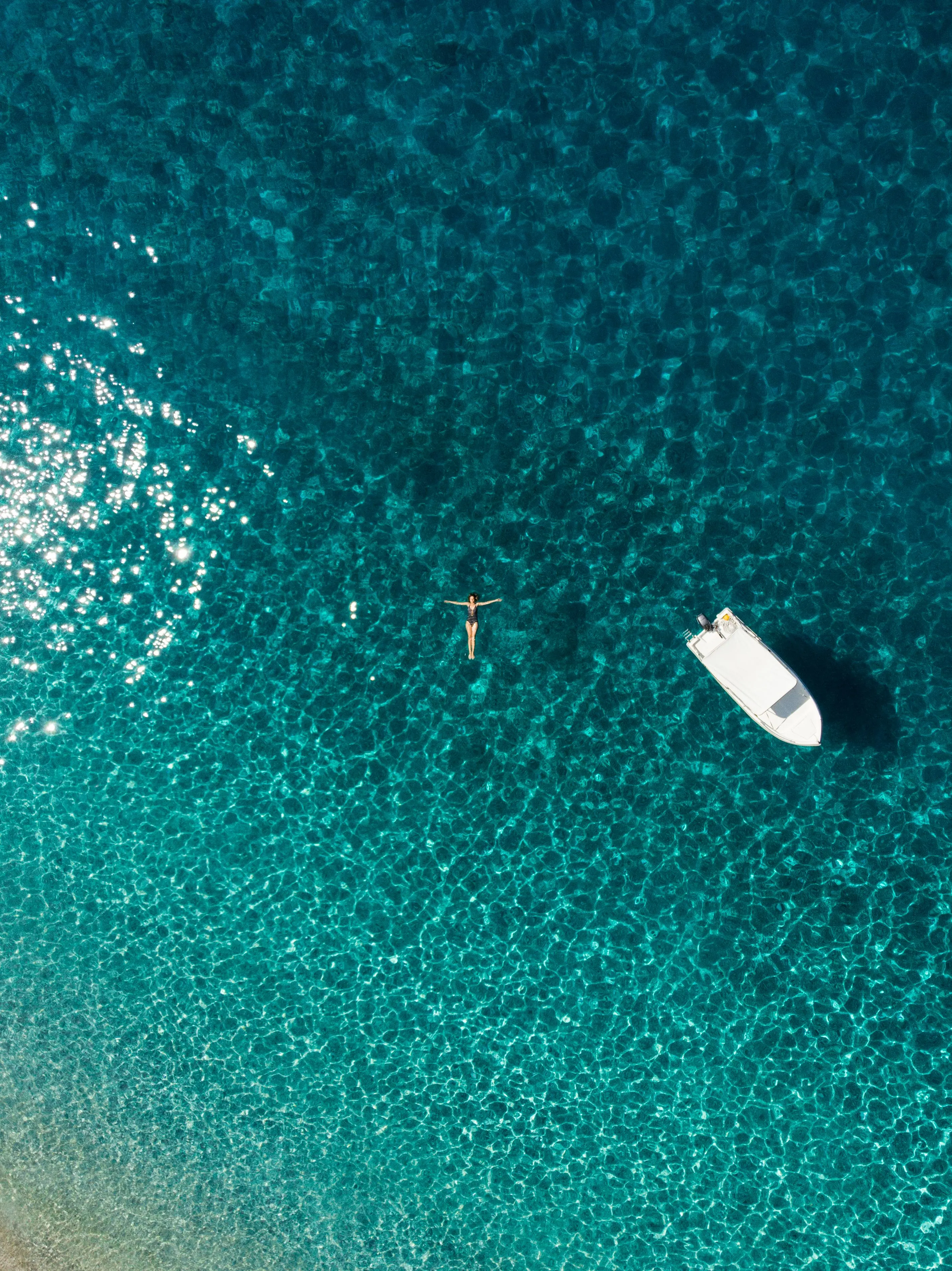 Boat on clear Mediterranean water, seen from above