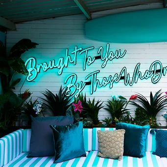 Neon script above striped seating on a bar terrace
