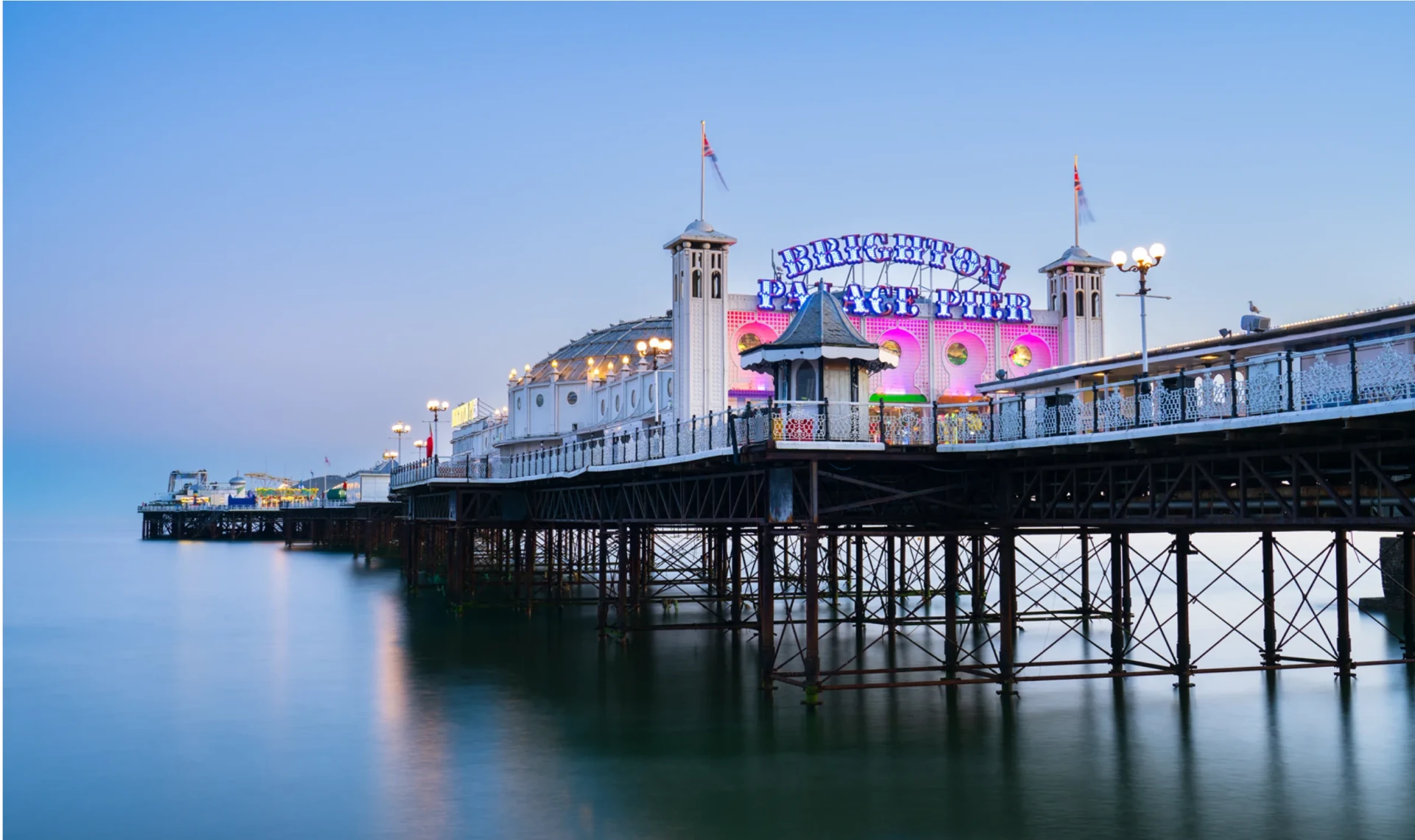 Brighton Palace Pier lit up at dusk, seen from the beach