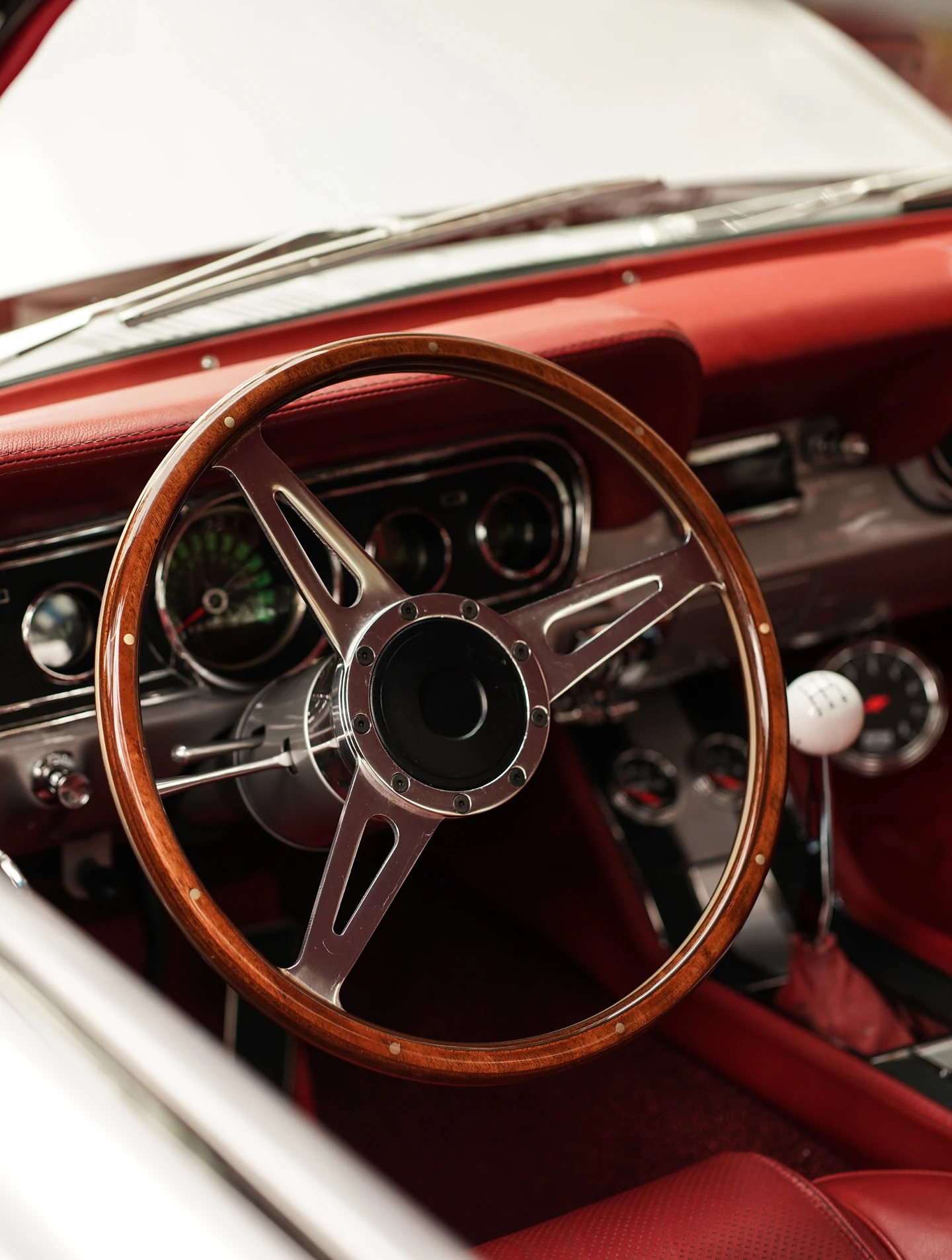 Wooden steering wheel of a classic car, red leather interior behind